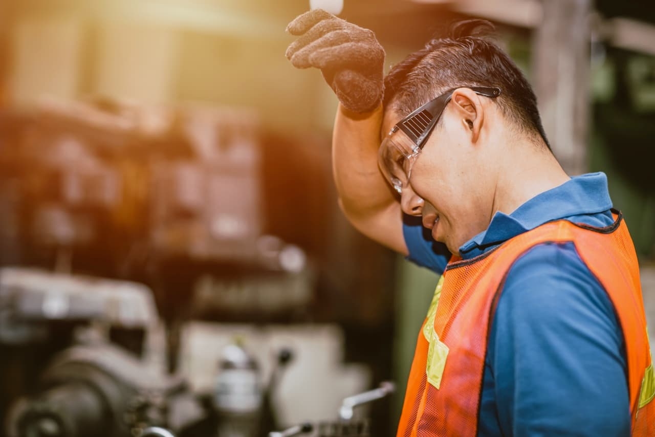 Ingeniero en una fábrica inspeccionando piezas bajo una luz intensa, donde las soluciones de ventilación de Bioclimex son esenciales en México.