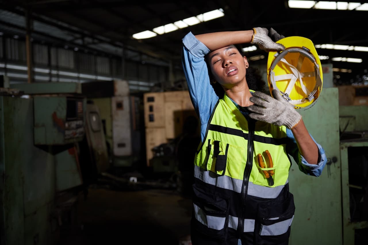 Trabajador descansando y limpiando el sudor en una fábrica, un entorno que se beneficia de los sistemas de aire acondicionado de Bioclimex en México.