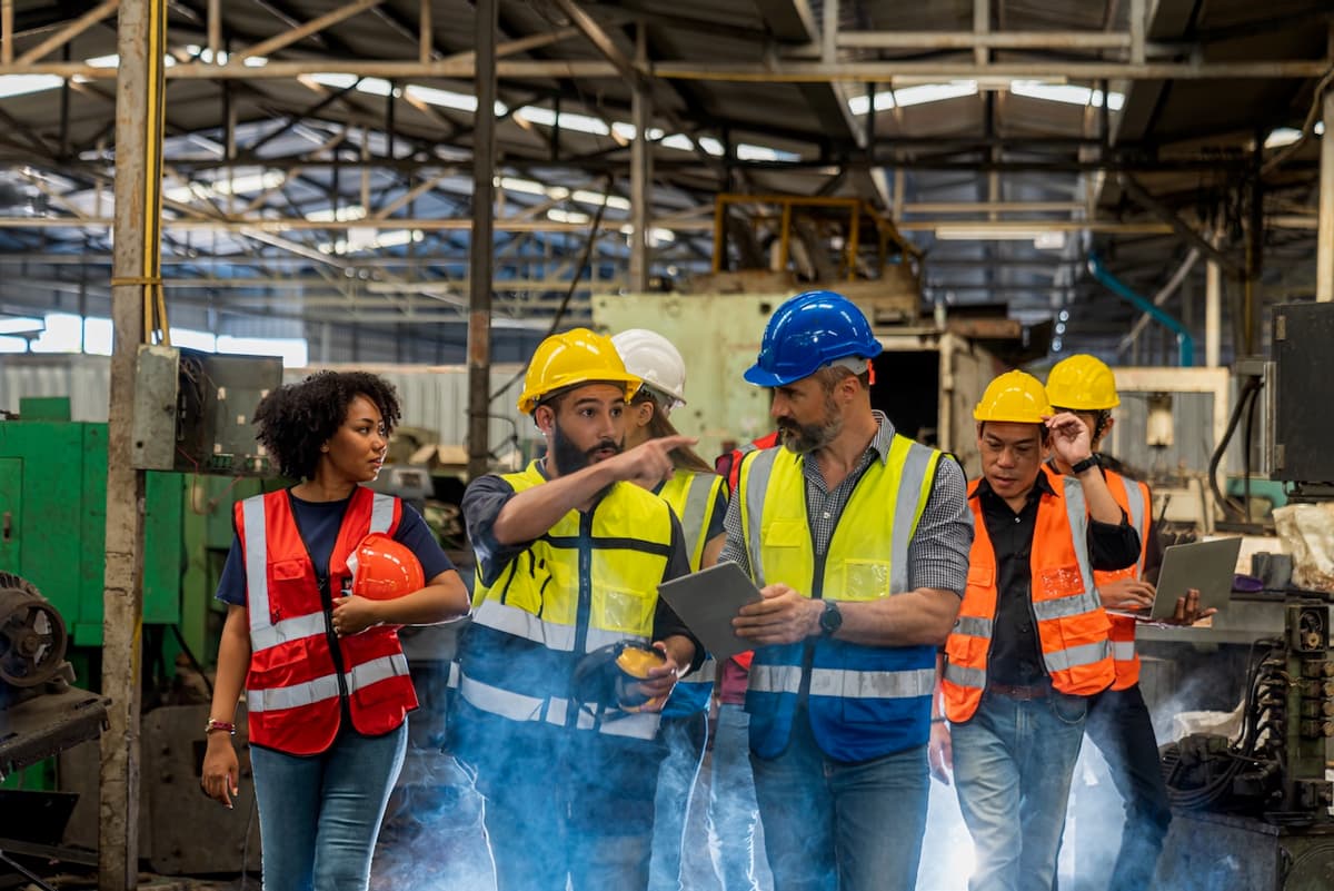 Equipo de trabajadores de construcción con cascos y chalecos conversando en una obra, representando proyectos de Bioclimex en áreas industriales en México.