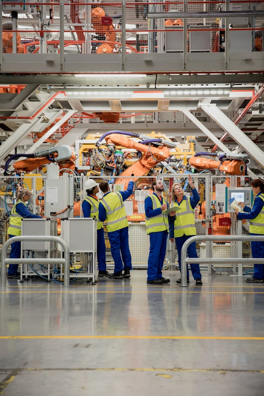 Trabajadores en una línea de montaje de automóviles dentro de una fábrica, un ambiente ideal para implementar sistemas de ventilación industrial de Bioclimex en México.