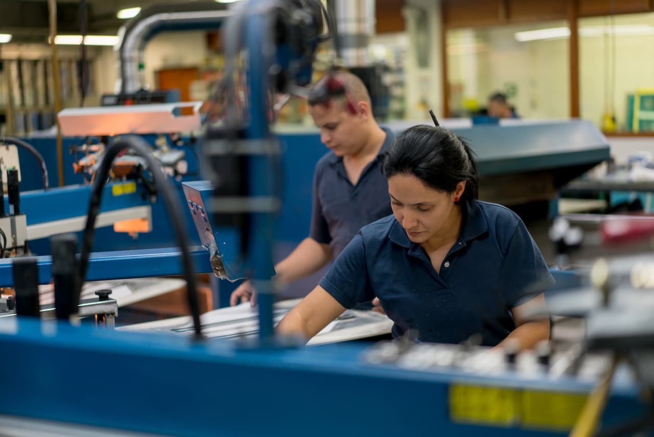 Trabajadora en una fábrica operando maquinaria con concentración, un entorno adecuado para las soluciones de aire acondicionado de Bioclimex en México.